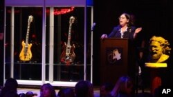 FILE - Guernsey's auctioneer Joanne Grant conducts bidding on guitars previously owned by the late Jerry Garcia during an auction, May 8, 2002, at Studio 54 in New York. The guitar named "Wolf," left, sold for over $700,000.