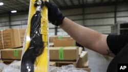 A field operations officer inspects a suspect hair accessory at a centralized exam station in Newark, N.J., July 1, 2020, U.S. Customs and Border Protection detained a shipment of weaves believed to be made in a Chinese detention camp, June 29, 2020.