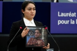 Jewher Ilham, daughter of imprisoned Uighur scholar Ilham Tohti holds a photo of her father during the Sakharov Prize ceremony at the European Parliament, in Strasbourg, eastern France, Wednesday, Dec. 18, 2019.