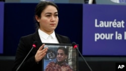 FILE - Jewher Ilham, daughter of Uyghur scholar Ilham Tohti holds a photo of her father during the Sakharov Prize ceremony at the European Parliament, in Strasbourg, France, Dec. 18, 2019. This week marks 10 years since Chinese authorities sentenced Ilham Tohti to life in prison.