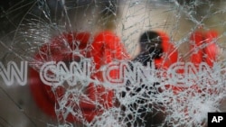 A security guard walks behind shattered glass at the CNN building at the CNN Center in the aftermath of a demonstration against police violence on May 30, 2020, in Atlanta.