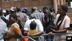 FILE - Customers wait in a queue to withdraw cash from a bank in Harare, Zimbabwe, after the Reserve Bank of Zimbabwe issued new banknotes, Tuesday, Nov, 12, 2019.