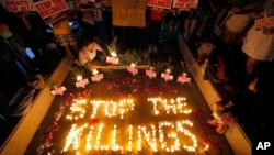 FILE - Human rights activists light candles for the victims of extrajudicial killings around the country in the wake of the "war on drugs" campaign by Philippine President Rodrigo Duterte in suburban Quezon city northeast of Manila, Philippines. 