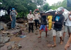 People carry a man injured during a flood in Ile Ape, on Lembata Island, East Nusa Tenggara province, Indonesia, April 4, 2021.