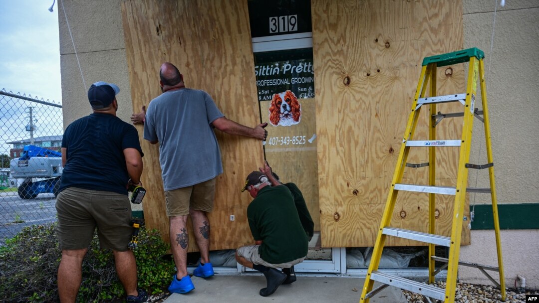 Los empleados de una tienda protegen su negocio en Kissimmee, Florida, el 8 de octubre de 2024, antes de la llegada prevista del huracán Milton.