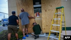 Los empleados de una tienda protegen su negocio en Kissimmee, Florida, el 8 de octubre de 2024, antes de la llegada prevista del huracán Milton.