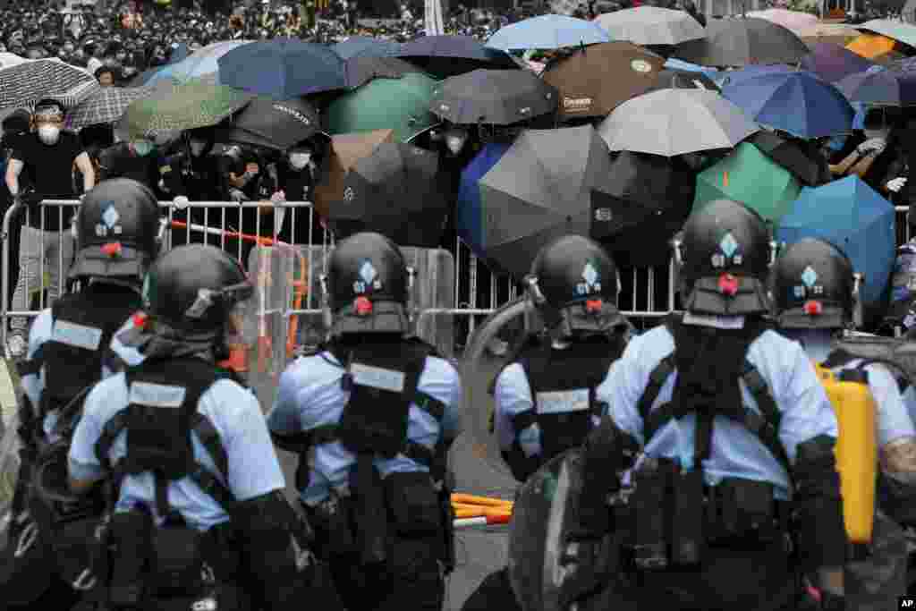 2019年6月12日在香港立法会附近，带有防暴装备的警察同打着雨伞的示威者对峙。