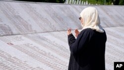 FILE - Djulija Jusic, who lost two sons and thirty three other relatives in the Srebrenica massacre, prays by their names at the memorial cemetery in Potocari, near Srebrenica, eastern Bosnia, June 8, 2021. 