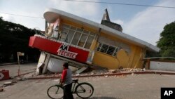 FILE - A man walks his bike past a building felled by a 7.1 earthquake in Jojutla, Morelos state, Mexico, Sept. 20, 2017.