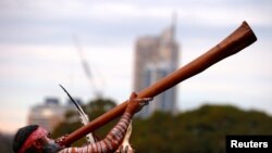 Seorang pria dari suku asli Aborigin memainkan alat musik didgeridoo upacara penyambutan di kantor pemerintahan di Sydney, Australia, pada 28 Juni 2017. (Foto: Reuters/David Gray)