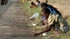 FILE - In this Dec. 14, 2008 file photo, children and their parents pick corn kernels spilled on the roadside by trucks ferrying corn imported from South Africa, in Masvingo 239 kilometers (148.5 miles) south of Harare.