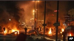 Protesters throw stones during clashes with riot police close to a tax office in Ettadhamen, Tunisia, 5 kms (3 miles) from Tunis, Friday, Jan. 10, 2014. 