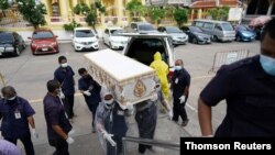 Temple workers carry a coffin containing a body of a man who died from the coronavirus disease (COVID-19) during his funeral at a temple in Bangkok, Thailand, April 24, 2021.