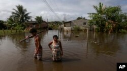 Residents wade through flood waters in an attempt to return to their homes in a rural area of Ilheus, Bahia state, Brazil, Dec. 30, 2021. 