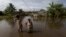 Residents wade through flood waters in an attempt to return to their homes in a rural area of Ilheus, Bahia state, Brazil, Dec. 30, 2021. 