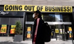 A man wearing a mask walks by Century 21 department store, Sept. 30, 2020 in the Brooklyn borough of New York. The discount department store chain has filed for Chapter 11 bankruptcy protection and is closing its 13 stores.