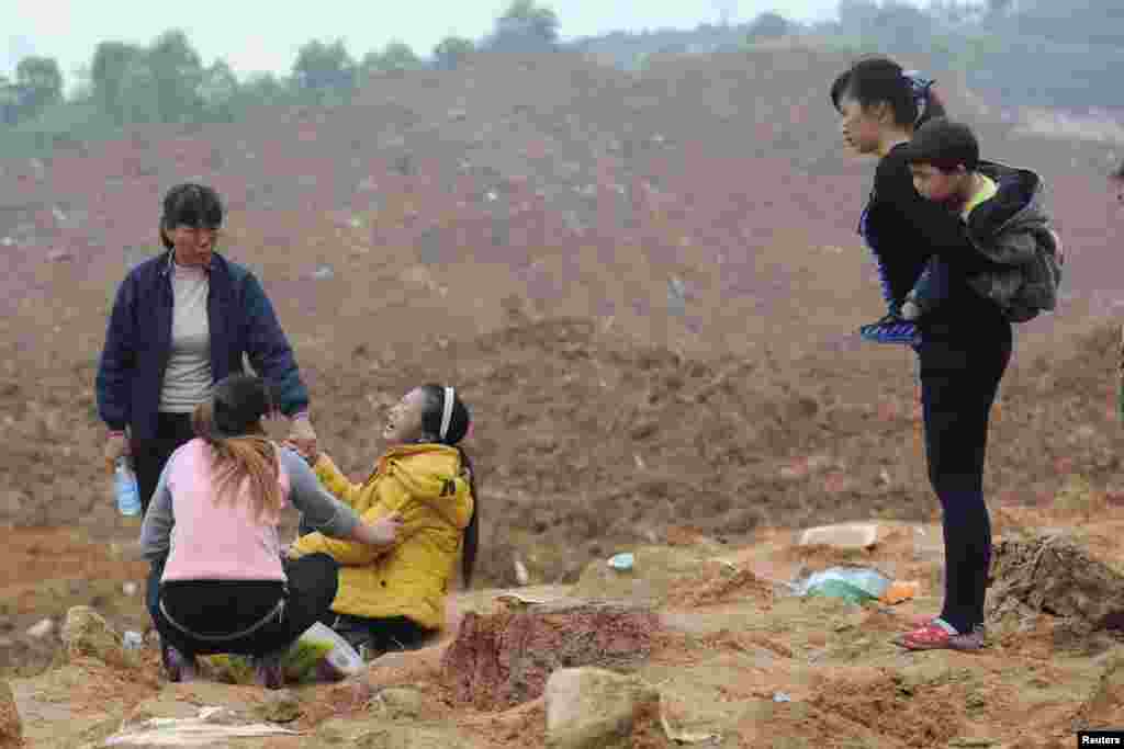 A woman (3rd L), who is a relative of several missing people, cries at the site of a landslide that hit an industrial park in Shenzhen, Guangdong province, China. More than 70 people are still missing.