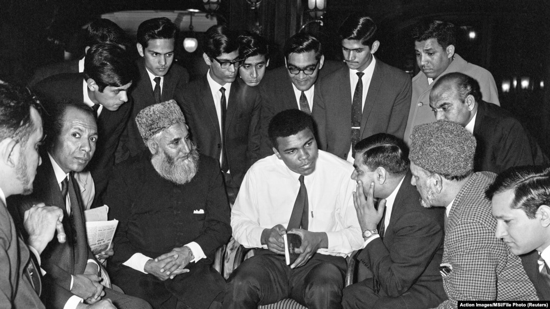 Muhammed Ali 1966'ta Londra'da Müslümanlarla sohbet ederken. Elindeki Ebu'l Ala Mevdudi'nin İslam'ı Anlamaya Doğru kitabı var