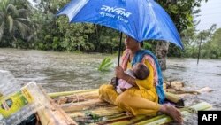 বন্যা-প্লাবিত ফেনীতে একজন নারী ও তার শিশু ভেলায় করে নিরাপদ স্থানে যাচ্ছেন। ফটোঃ ২২ অগাস্ট, ২০২৪। 