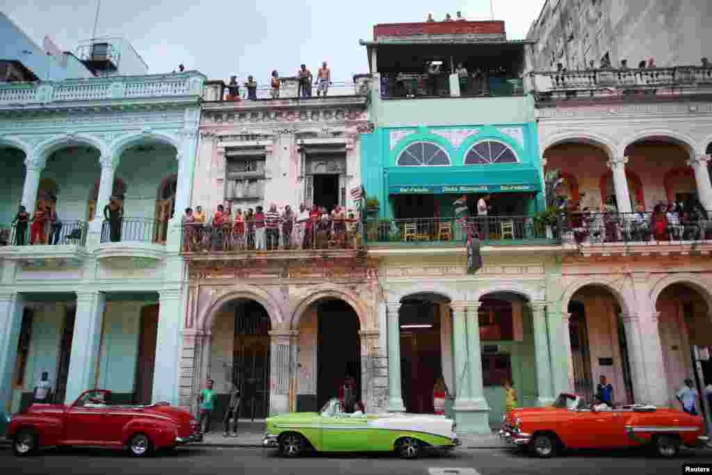 Orang-orang berdiri di balkon untuk menyaksikan peragaan busana oleh perancang Jerman Karl Lagerfeld sebaga bagian dari koleksi antar musim Cruise yang terbaru yang dibuat untuk rumah mode Chanel di jalan Paseo del Prado di Havana, Kuba, 3 Mei 2016.