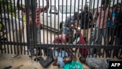 Burundian students slide under the main access gate of the American Embassy in Bujumbura, June 25, 2015. 