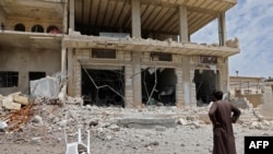 FILE - A man stares at a building damaged during reported shelling by government and allied forces, in the town of Hbeit in the southern countryside of the rebel-held Idlib province, May 3,2019. 