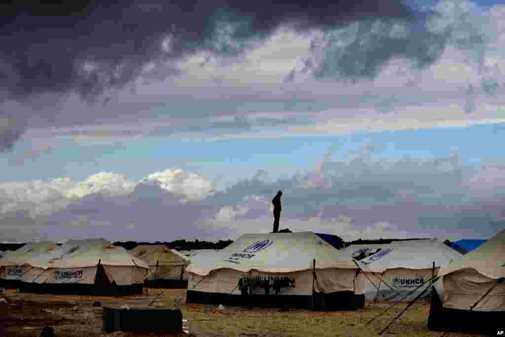 A Syrian refugee stands on top of a water tank at Zaatari refugee camp, near the Syrian border in Mafraq, Jordan. 