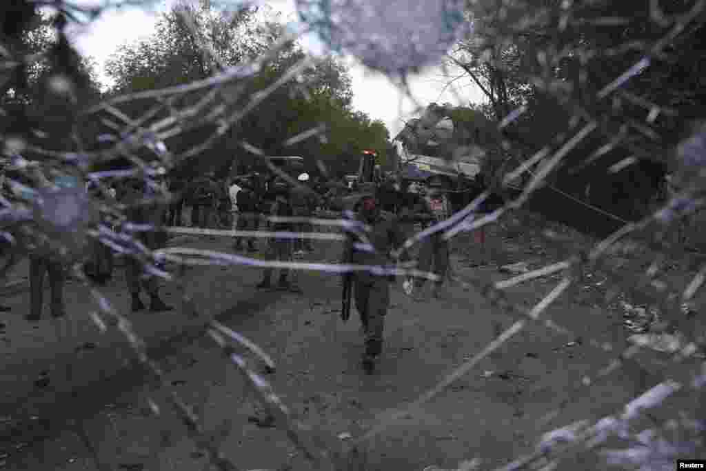 Afghan police are seen through the damaged car windshield at the site of a suicide car bomb attack in Kabul, June 11, 2013. 