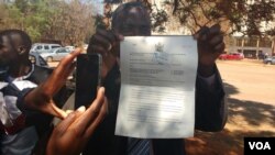 Zimbabwe People First Lawyer Gift Nyandoro attempts to hand over a court order granting opposition parties permission to state a protest.