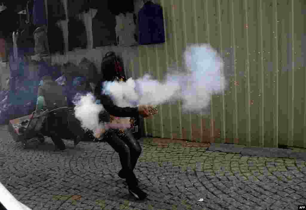 A Kurdish student protester launches fireworks against Turkish riot policemen in downtown Istanbul during an anti-government protest marking the second anniversary of a Turkish military air strike aimed at Kurdish rebels that killed 34.