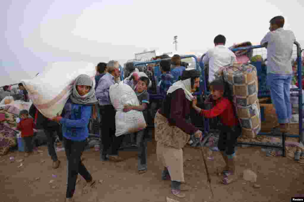 Newly arrived Syrian Kurdish refugees carry their belongings after crossing into Turkey near the southeastern town of Suruc in Sanliurfa province, Sept. 22, 2014. 