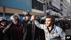 An Egyptian anti-government activist shakes hands with riot police officers after the police pulled back following clashes with protesters in Cairo, Egypt, Jan 28, 2011