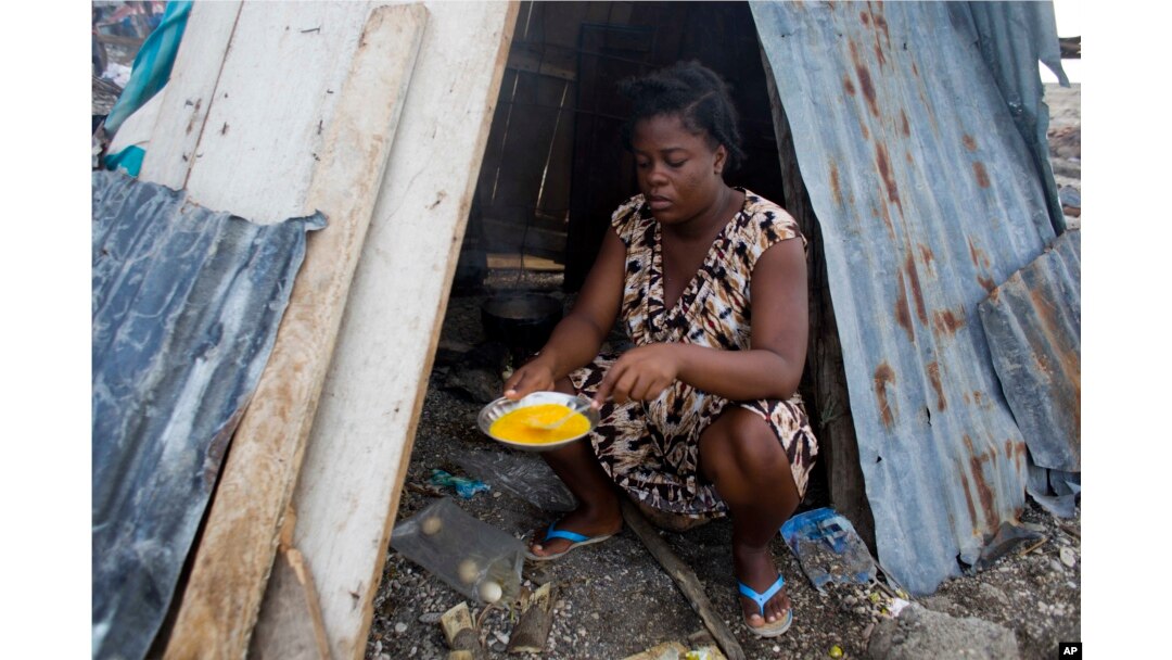 FILE - Nathanaelle Bernard, 19 and pregnant, cooks an omelet in a makeshift hut shared with five family members in Coteaux, Haiti, Nov. 1, 2016. Hurricane Matthew destroyed her home weeks earlier.
