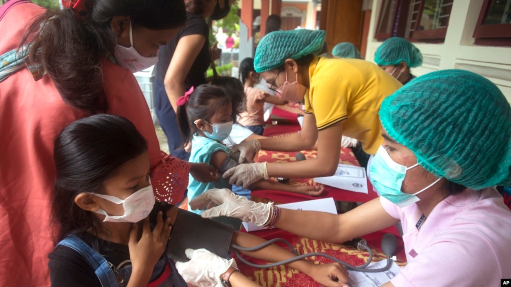 Siswa memeriksakan kesehatannya sebelum menerima vaksin Sinovac COVID-19 saat kampanye vaksinasi di sebuah sekolah dasar di Bali pada Kamis, 23 Desember 2021. (Foto: AP/Firdia Lisnawati)