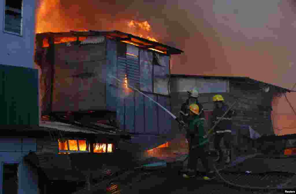 Firemen try to extinguish a fire as houses burn in a squatter colony in Quezon City, Metro Manila.