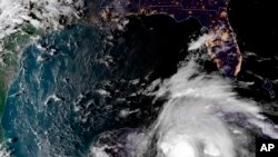 This satellite image provided by the National Oceanic and Atmospheric Administration shows a view of Tropical Storm Michael, lower right, churning as it heads toward the Florida Panhandle, Sunday, Oct. 7, 2018, at 6:52 p.m.
