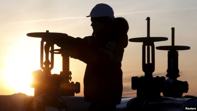 FILE - A worker checks the valve of an oil pipe outside the West Siberian city of Kogalym, Russia, Jan. 25, 2016.