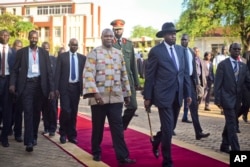 FILE - South Sudan's rebel leader and now Vice President Riek Machar, center-left, walks with President Salva Kiir, center-right, after being sworn in at the presidential palace in the capital Juba, South Sudan, April 26, 2016.