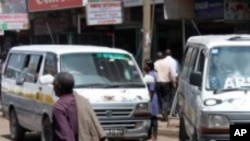 A man walks past two Kenyan minibuses in Nairobi.
