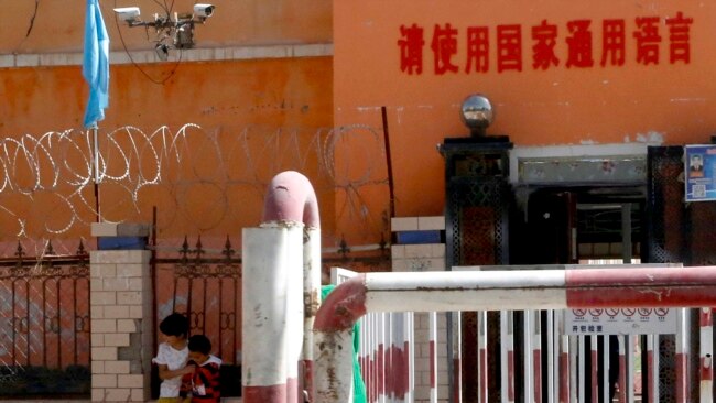 新疆喀什地区伽师县一所小学校门有铁丝网和监控镜头,校门前写着:请使用国家通用语言。(2018年8月31日)