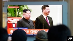 Moun Kore di Sid, Swoul, kap gade lidè Kore di Nò a Kim Jong Un ka Prezidan chinwa a, Xi Jinping. 8 janvye 2019. (FotoAP/Ahn Young-joon)
