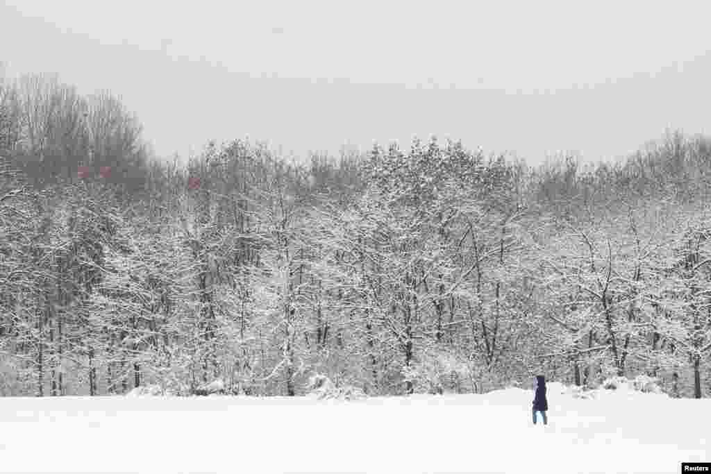 A woman walks in a park during snowfall in Sofia, Bulgaria.