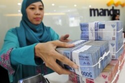 Kasir di kantor cabang Bank Mandiri menangani mata uang Rupiah pada transaksi di Jakarta 20 Juli 2015. (Foto: Antara via Reuters)