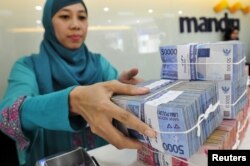 Seorang teller di cabang Bank Mandiri menangani mata uang Rupiah saat bertransaksi di Jakarta. (Foto: Antara via Reuters)