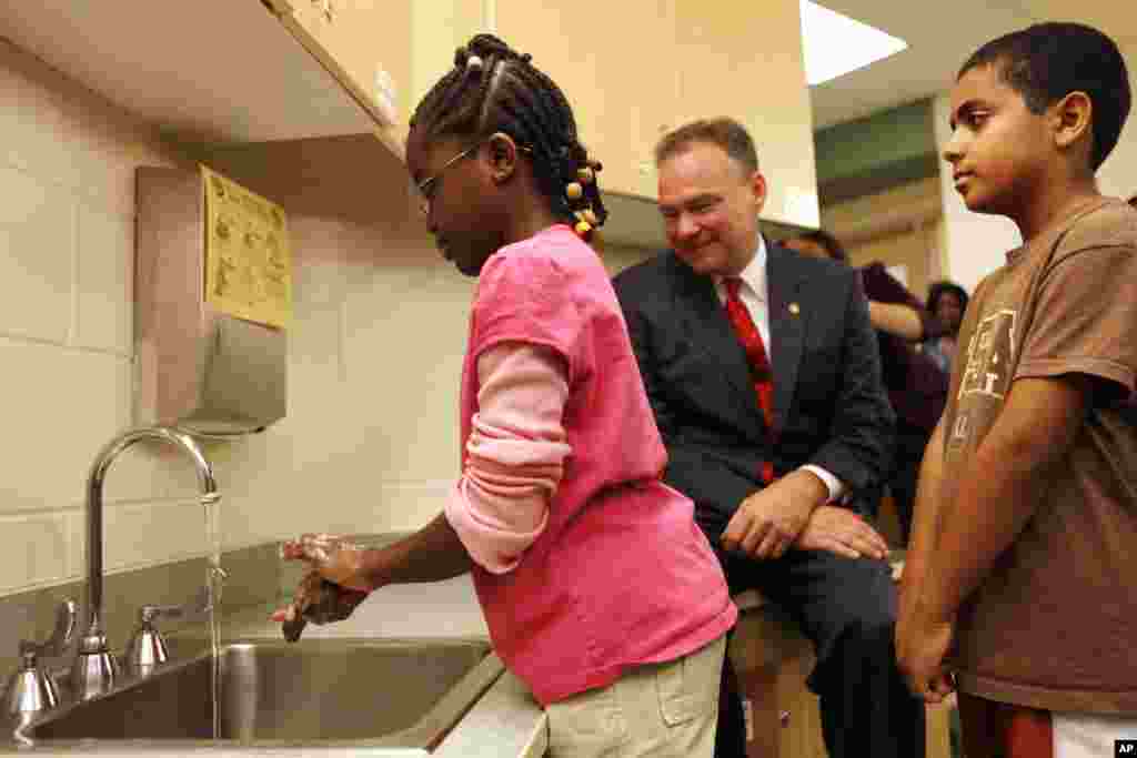 Michelle Marfo, 9, of Alexandria, Virginia, left, demonstrates her hand washing technique to Gov. Tim Kaine after the governor spoke about the H1N1 virus at Samuel Tucker Elementary School in Alexandria, Sept. 1, 2009.