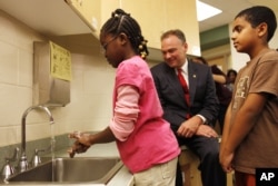 FILE - Michelle Marfo, 9, of Alexandria, Va., left, demonstrates her hand washing technique to Virginia Gov. Tim Kaine as Mased Saroor, 9, waits his turn, after the governor spoke about the H1N1 virus at Samuel Tucker Elementary School in Alexandria, Va. Sept. 1