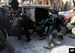 Ukrainian police officers try to take away tires from activists who want to set it on fire during a protest at the presidential administration in Kyiv, April 8, 2016. The demonstrators demanded that the government take stronger efforts to combat corruption.