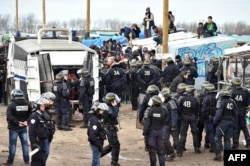 Anti-riot policemen face migrants during the dismantling of half of the "Jungle" migrant camp in the French northern port city of Calais, Feb. 29, 2016.