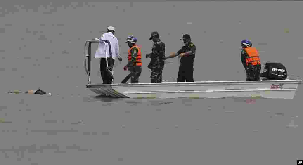 Rescue workers recover the body of a plane crash victim in the Mekong River in Pakse, Laos, Oct. 18, 2013. 