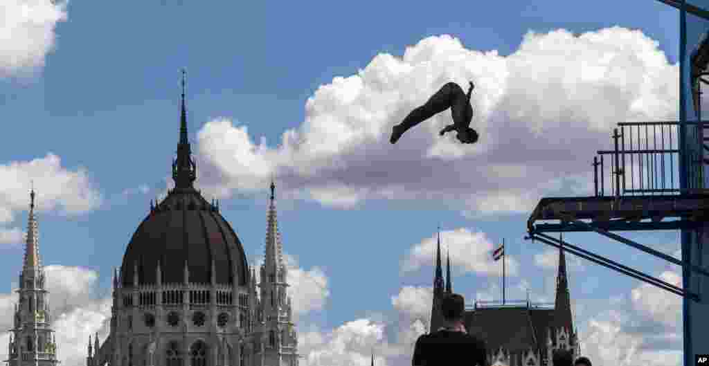 Seorang atlet lompat indah berlatih di kolam renang lapangan Batthyany dengan latar belakang gedung parlemen Hungaria di Budapest.